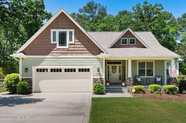 craftsman inspired home with a porch, concrete driveway, stone siding, and a front lawn