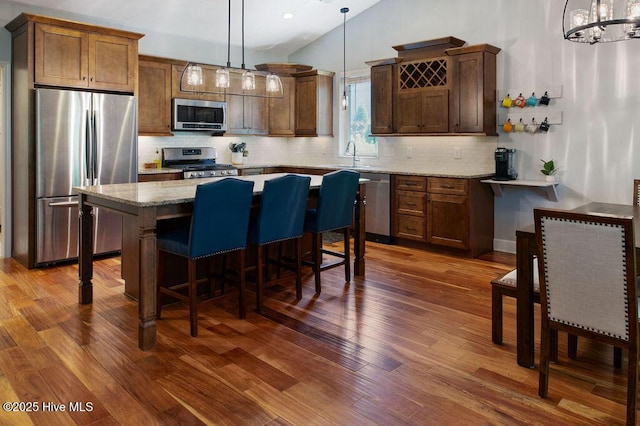 kitchen with a kitchen island, stainless steel appliances, dark wood-style floors, and tasteful backsplash