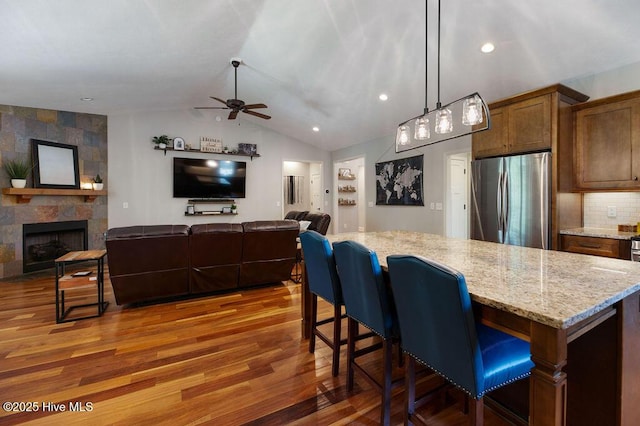 kitchen featuring light stone counters, freestanding refrigerator, a ceiling fan, and wood finished floors