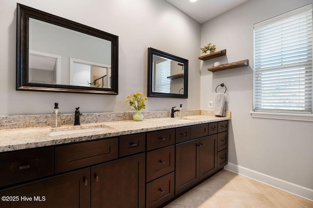 full bath with double vanity, baseboards, and a sink