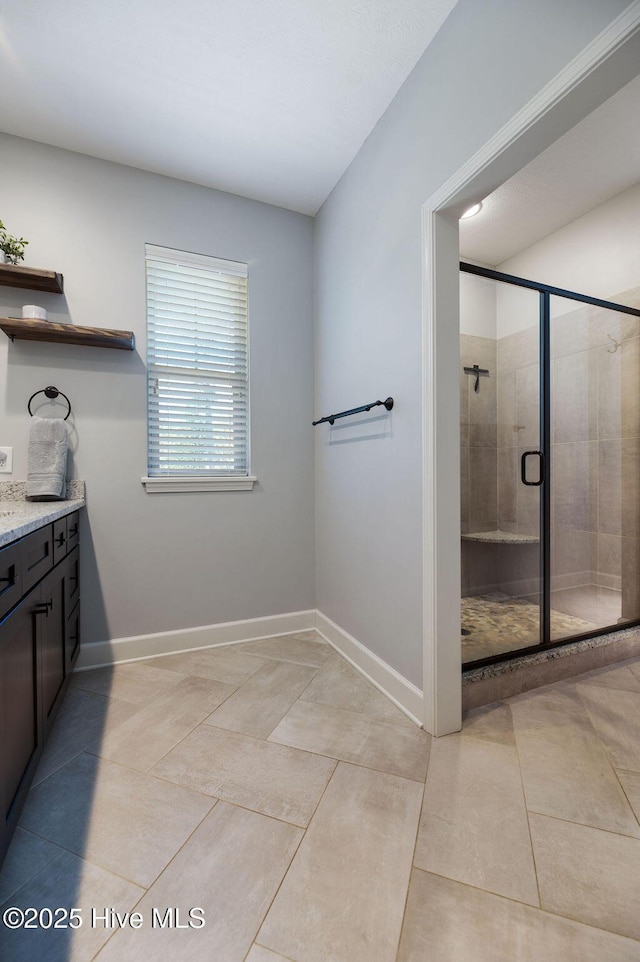 full bathroom featuring vanity, tile patterned floors, baseboards, and a stall shower