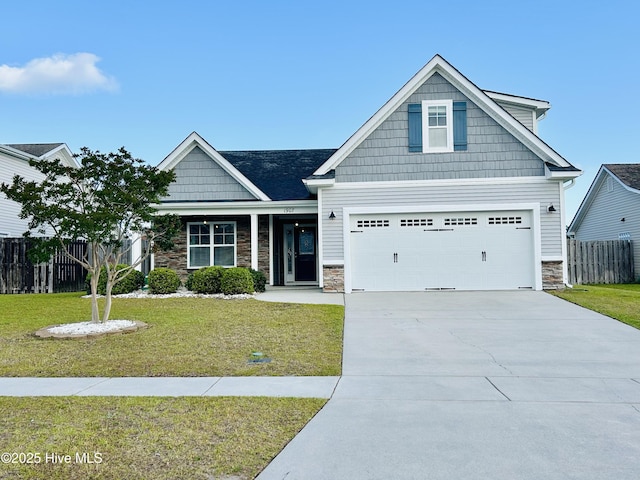 craftsman inspired home featuring fence, a front yard, driveway, and stone siding