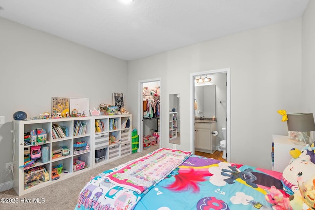 carpeted bedroom with a sink, a closet, connected bathroom, and a spacious closet