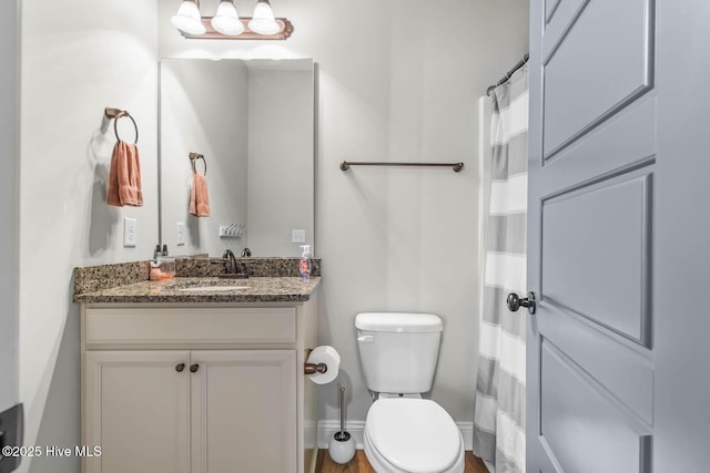 bathroom with vanity, baseboards, toilet, and curtained shower