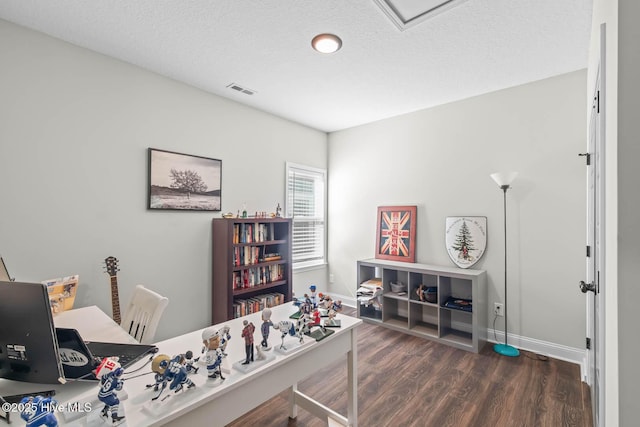 office area with baseboards, a textured ceiling, wood finished floors, and visible vents