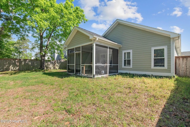 back of house with a lawn, a fenced backyard, and a sunroom