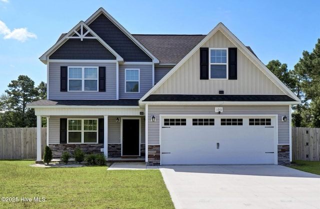 craftsman-style home featuring fence, a front lawn, stone siding, board and batten siding, and driveway