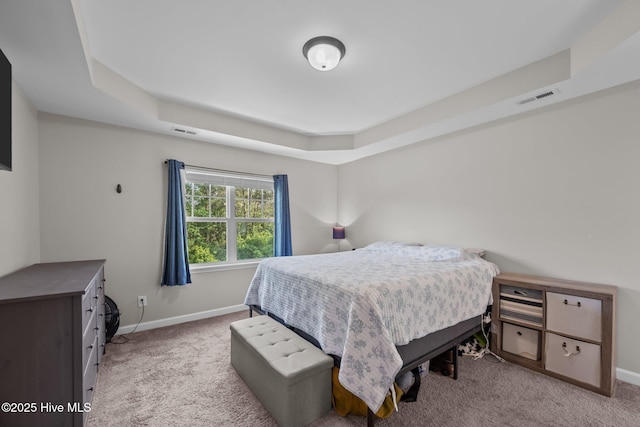 bedroom featuring visible vents, a raised ceiling, baseboards, and light colored carpet