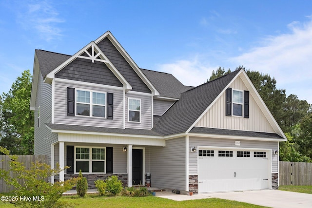 craftsman house with a porch, fence, driveway, and stone siding