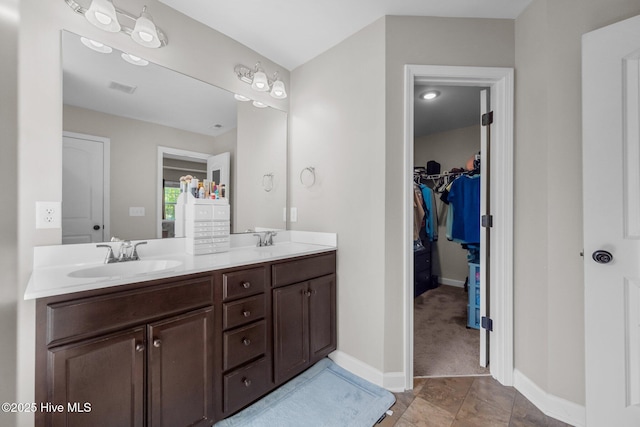 full bathroom featuring a sink, a walk in closet, double vanity, and visible vents