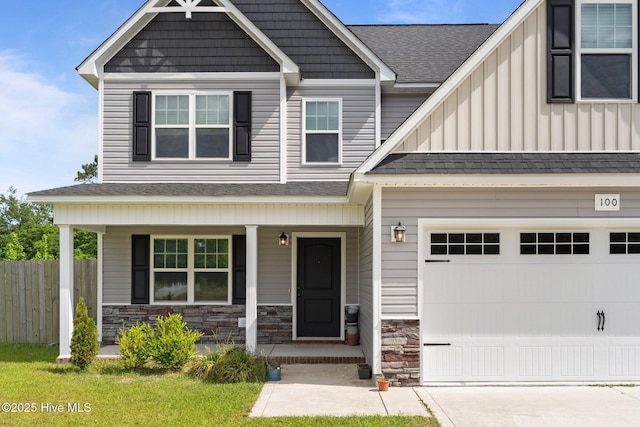 craftsman-style home featuring a porch, driveway, roof with shingles, fence, and stone siding