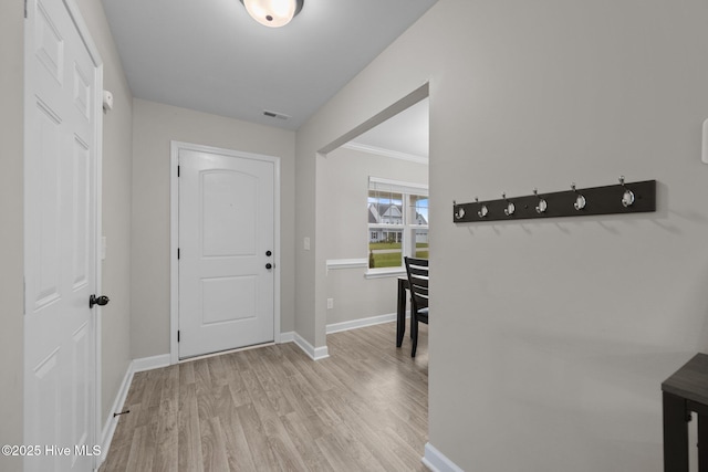 foyer entrance featuring baseboards, visible vents, ornamental molding, and wood finished floors