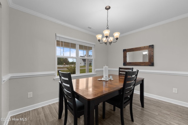 dining space with a notable chandelier, baseboards, wood finished floors, visible vents, and ornamental molding