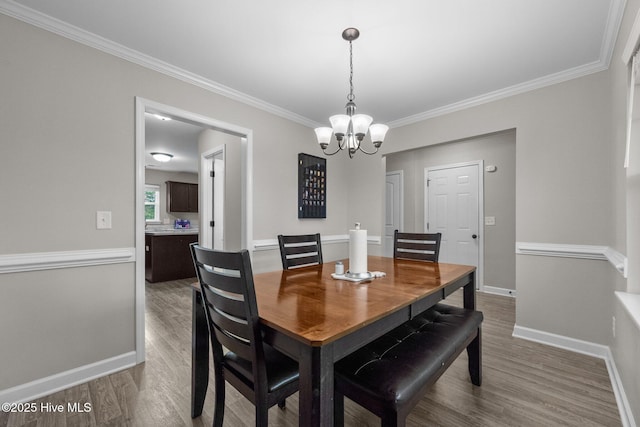 dining room featuring baseboards, crown molding, wood finished floors, and a notable chandelier