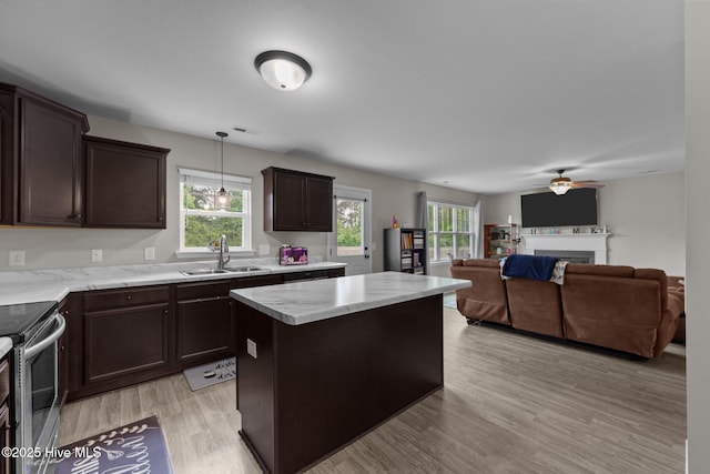 kitchen with a kitchen island, stainless steel electric range oven, light wood-type flooring, dark brown cabinets, and a sink
