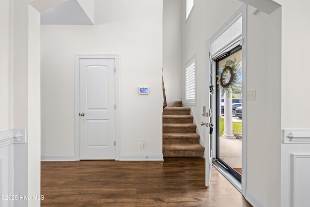 foyer entrance featuring stairs, baseboards, and wood finished floors