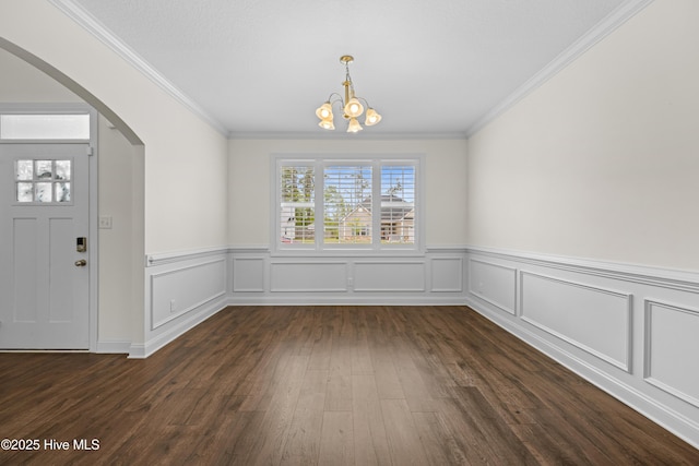 unfurnished dining area with plenty of natural light, arched walkways, a notable chandelier, and dark wood-style floors