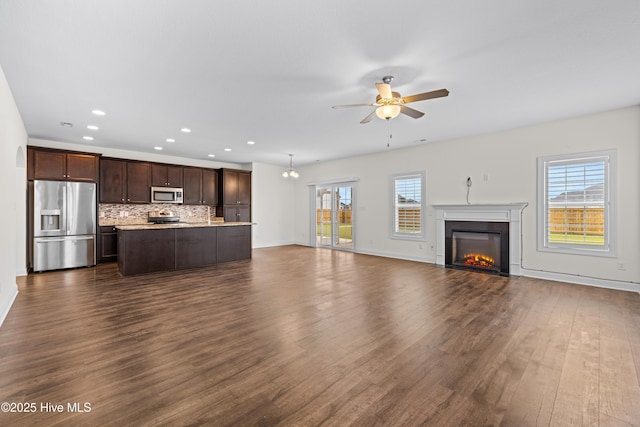 unfurnished living room featuring a ceiling fan, a fireplace with flush hearth, dark wood finished floors, baseboards, and recessed lighting
