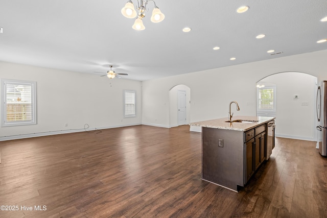 kitchen featuring arched walkways, dark wood-style floors, a sink, and stainless steel appliances