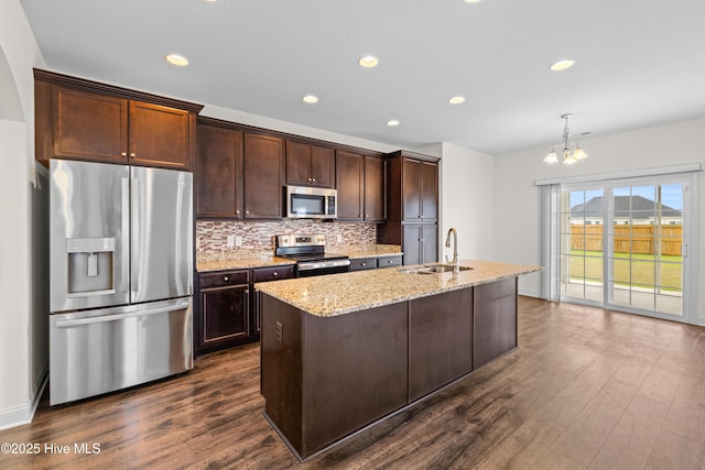 kitchen with dark brown cabinets, a sink, light stone counters, stainless steel appliances, and dark wood-type flooring