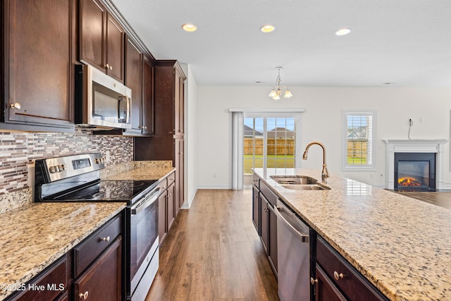 kitchen featuring dark wood-style floors, light stone counters, a sink, backsplash, and stainless steel appliances
