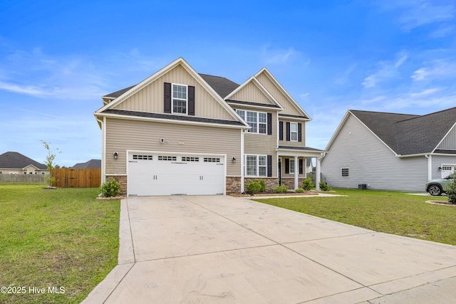 craftsman house featuring fence, a front lawn, stone siding, board and batten siding, and driveway