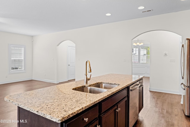 kitchen with visible vents, a sink, dark brown cabinets, arched walkways, and appliances with stainless steel finishes