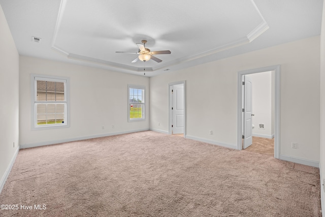 unfurnished bedroom with crown molding, light carpet, a raised ceiling, baseboards, and visible vents
