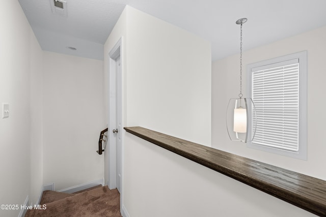 hall with carpet floors, baseboards, and visible vents