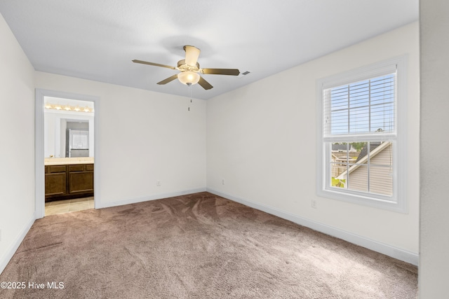 unfurnished bedroom with light carpet, a ceiling fan, baseboards, ensuite bathroom, and visible vents