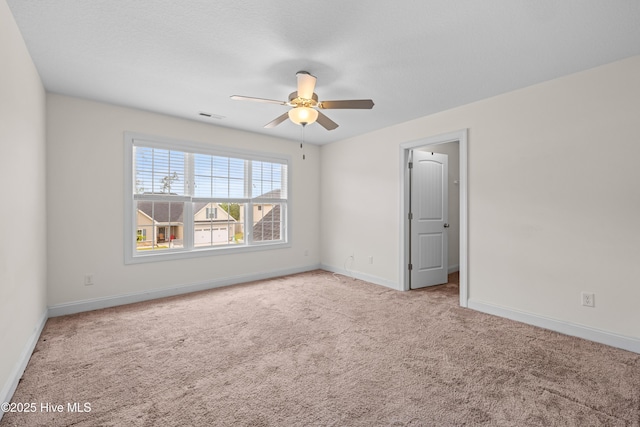 spare room with carpet flooring, ceiling fan, visible vents, and baseboards