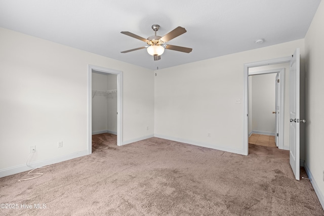 unfurnished bedroom with baseboards, carpet, and a spacious closet