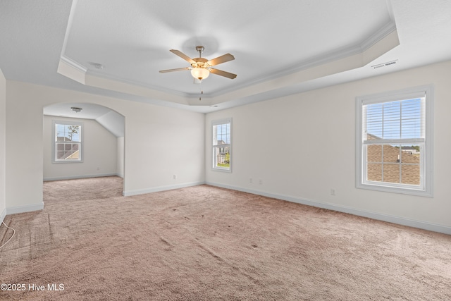carpeted spare room featuring visible vents, crown molding, ceiling fan, plenty of natural light, and a tray ceiling