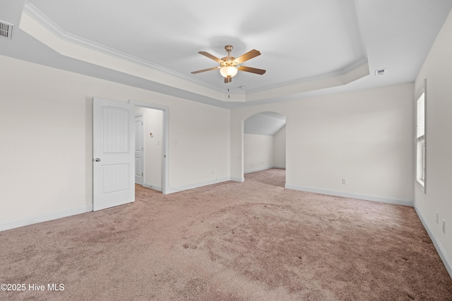 empty room featuring a raised ceiling, visible vents, a ceiling fan, and light colored carpet