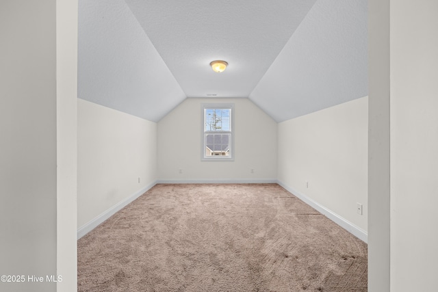 bonus room with carpet flooring, a textured ceiling, baseboards, and vaulted ceiling