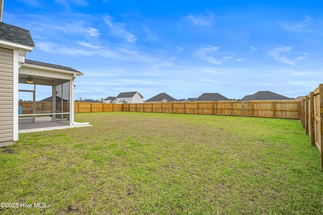 view of yard with a sunroom, a fenced backyard, and a ceiling fan