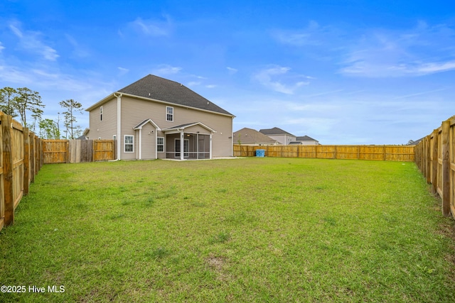rear view of house featuring a sunroom, a fenced backyard, and a lawn