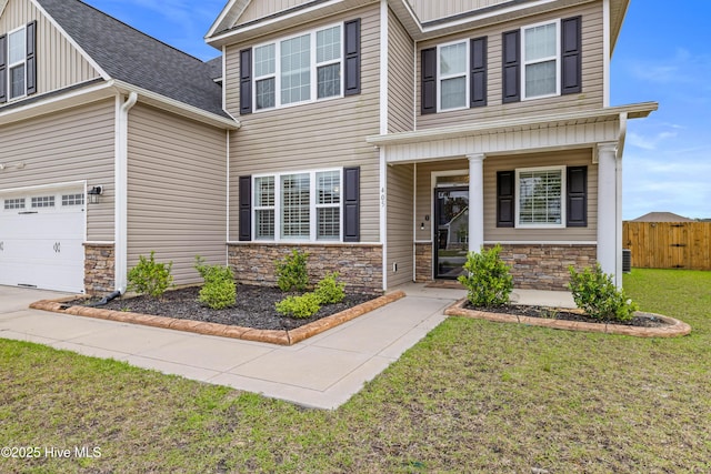 view of front of home featuring board and batten siding, a front yard, a garage, fence, and stone siding