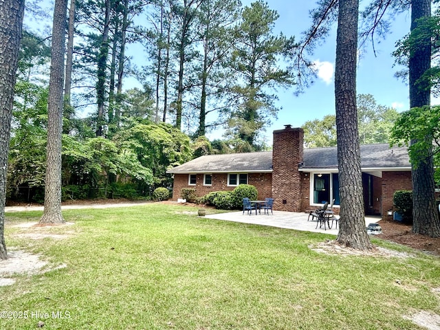 rear view of property featuring a lawn, brick siding, and a chimney