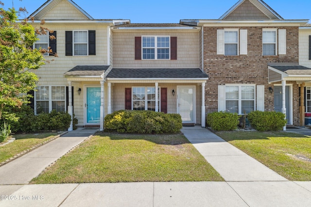 townhome / multi-family property featuring a shingled roof and a front yard