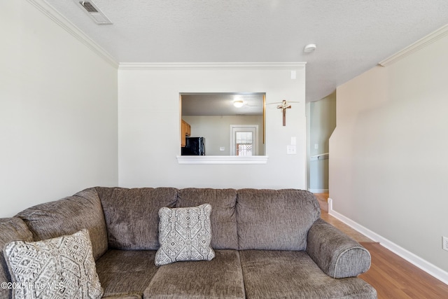 living area featuring crown molding, baseboards, wood finished floors, and visible vents