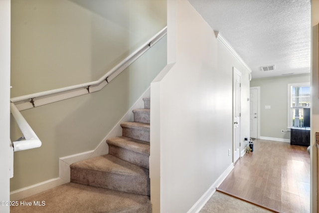 stairs with baseboards, wood finished floors, a textured ceiling, and visible vents