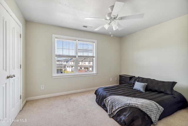 carpeted bedroom with baseboards, visible vents, ceiling fan, and a closet