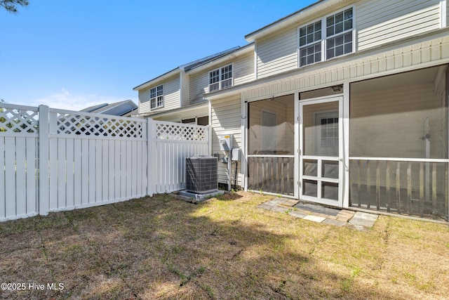 view of yard featuring a sunroom, a fenced backyard, and cooling unit