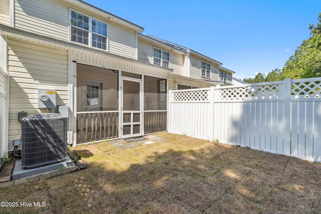 rear view of house featuring central air condition unit, fence, and a sunroom