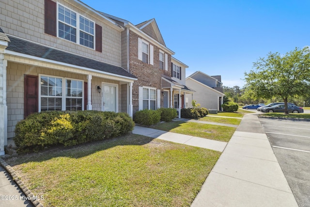 view of front facade with a shingled roof and a front lawn