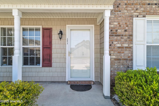 entrance to property featuring brick siding and covered porch