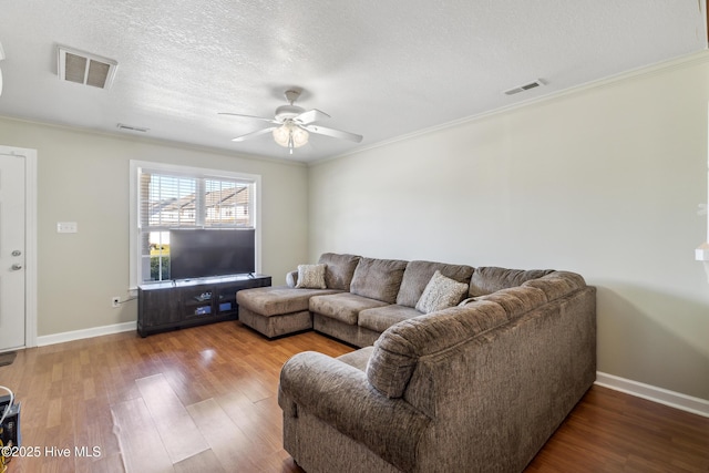 living room featuring visible vents, a ceiling fan, baseboards, and wood finished floors