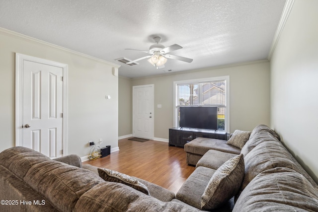 living area with a textured ceiling, ornamental molding, wood finished floors, and visible vents