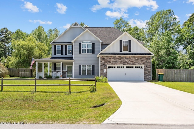 view of front of home with a porch, driveway, a front yard, fence, and stone siding